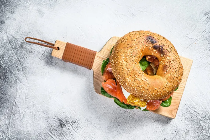 bagel sandwich with salmon, cream cheese, spinach and egg gray background top view