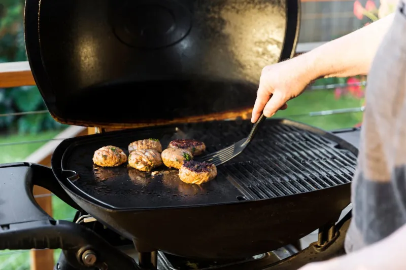man flipping burger on home barbecue setup