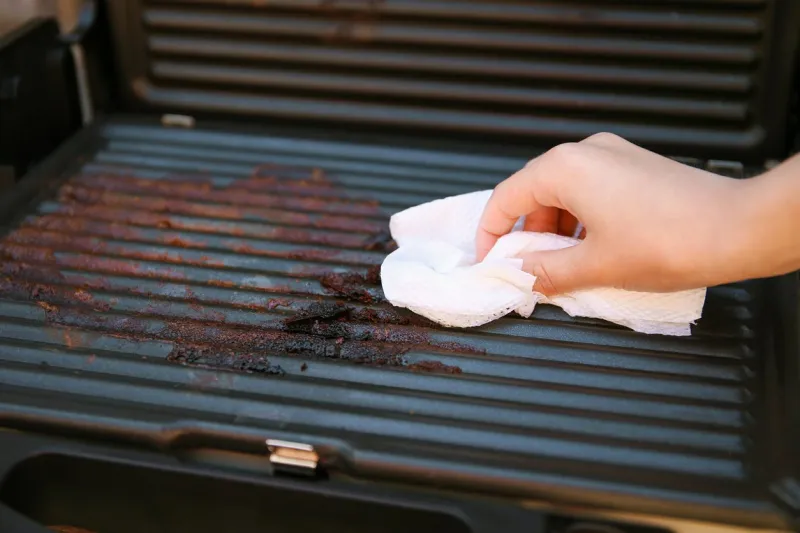 dirty electric grill female hand wiping with cloth grill