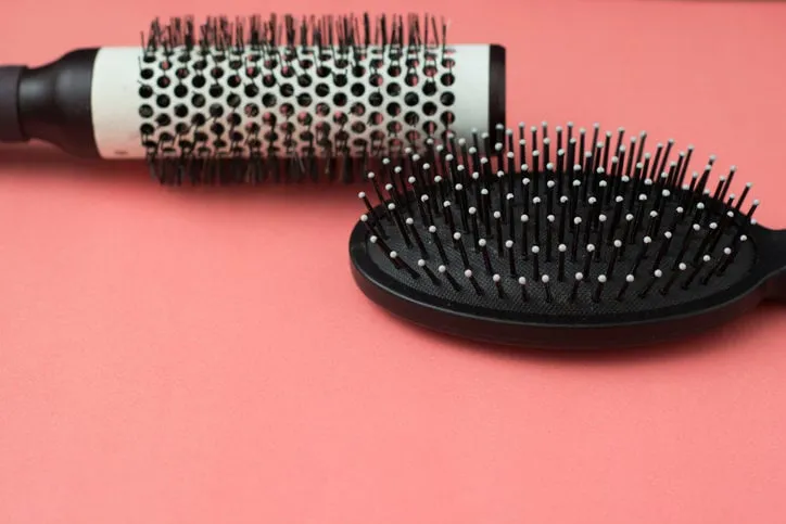 used hair brush tools on pink or coral background with copy space beauty fashion, hair care background