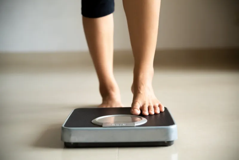 female leg stepping on weigh scales healthy lifestyle, food and sport concept