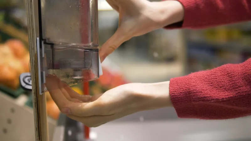 woman's hands close-up disinfects her hands with a sanitizer in a grocery supermarket and selects fresh fruit protection from the coronavirus pandemic rules of personal hygiene against covid-19