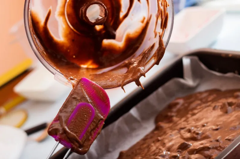 chef pouring cake batter in a baking tin, close up