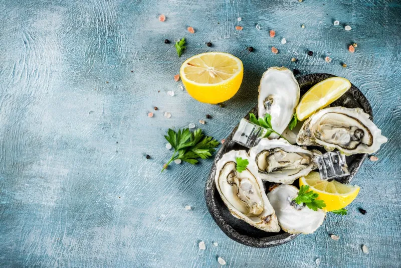 fresh raw seafood, oysters with lemon and ice on a light blue background