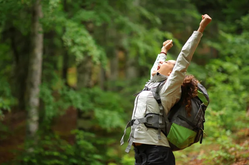 hiker excited raising arms celebrating in a forest