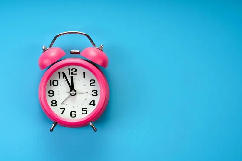 pink rustic alarm clock on blue background