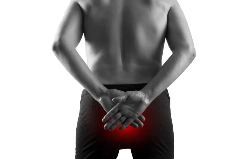 man suffering from hemorrhoids, anal pain, isolated on white background, painful area highlighted in red