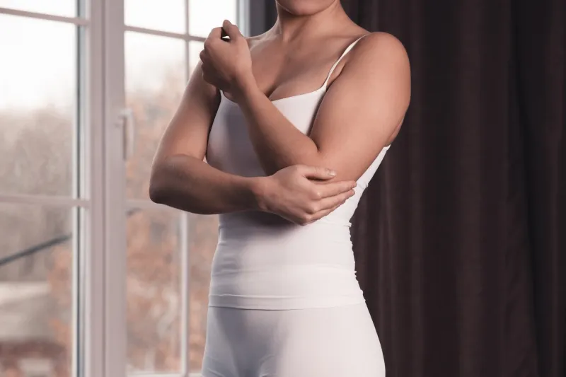 woman with pain in elbow, joint inflammation at home