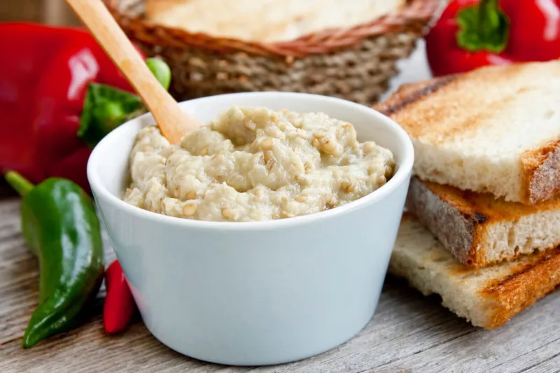 homemade creamy tasty eggplant salad with mayonnaise placed in a bowl with peppers and toast