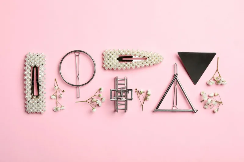 stylish hair clips and flowers on pink background, flat lay
