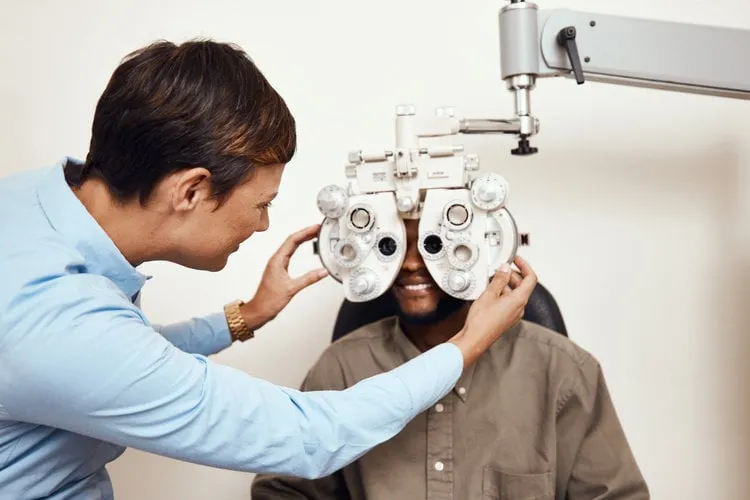 shot of an optometrist examining her patients eyes with an optical refractor