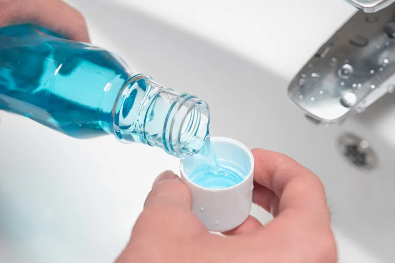 hand of man pouring bottle of mouthwash into cap