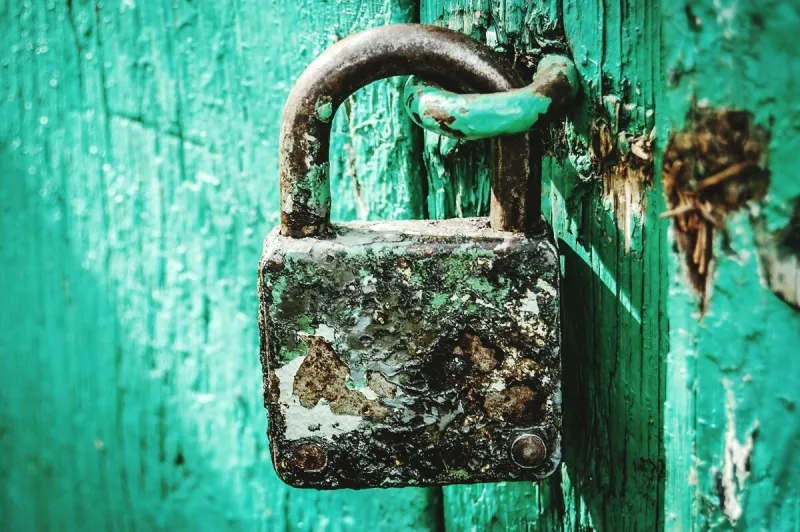 close-up of rusty padlock hanging on door