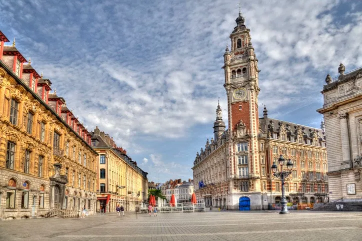 people walk on the place de theatre with the clock tower in the historical center of lille, france on may 27