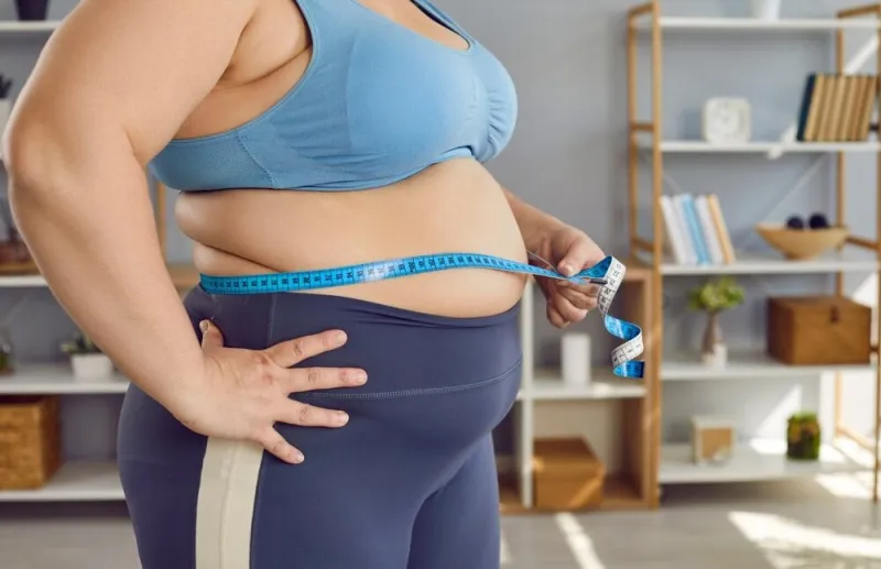 crop,shot,overweight,,obese,woman,in,sports,bra,holding,measuring