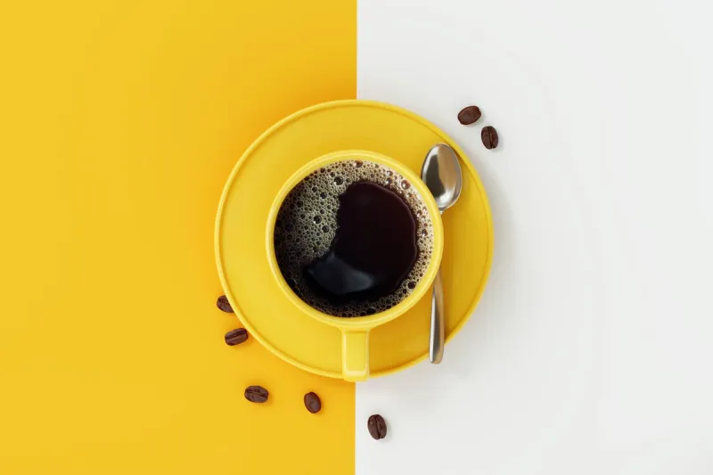 top view of coffee cup on yellow and white background