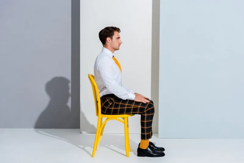 side view of man in checkered trousers sitting on white and grey