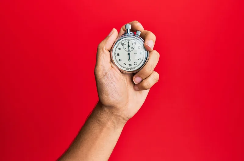 hand of young hispanic man using stopwatch over isolated red background