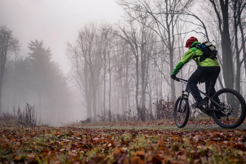 mountain biker on trail in woods bike rider in winter or autumn landscape forest man cycling mtb on rural country road sport fitness motivation and inspiration