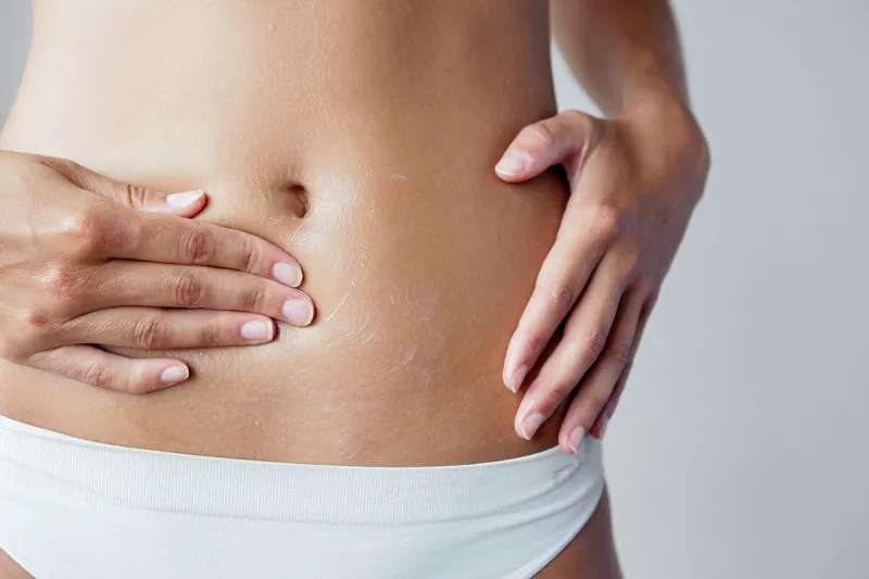 taille, hanche, ventre et jambe d'une femme sur fond neutre