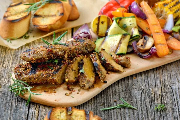 grilled vegan seitan steaks with mixed vegetables and crusty baguette