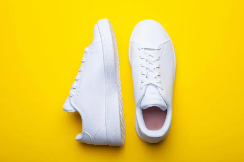 pair of casual shoes on yellow background top view of stylish s