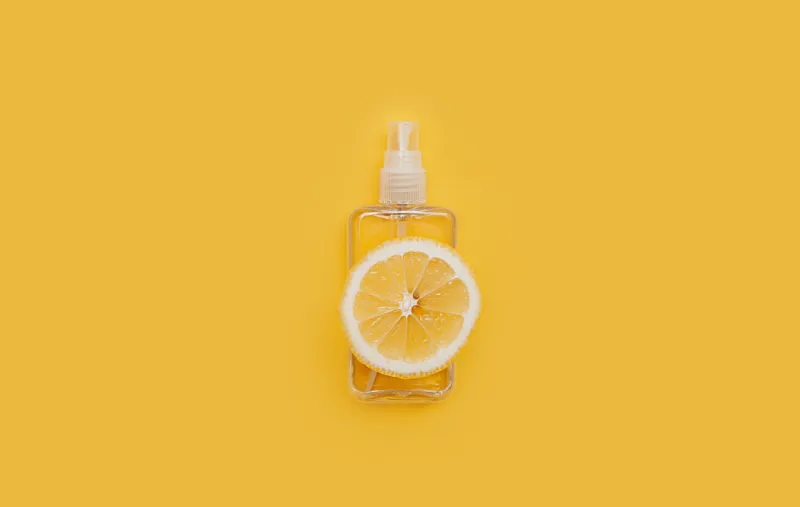 transparent spray jar with a round slice of fresh lemon on a yellow background, natural refreshment, purification and aromatization of the air