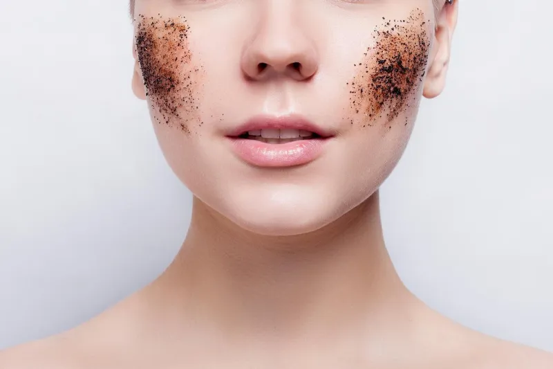 femme souriante aux cheveux courts, chauve nettoie la peau gommage au café, studio shot, portrait close-up