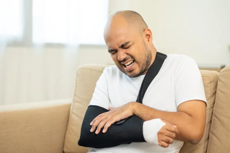 man suffered pain from accident fracture broken bone injury with leg splints in cast neck splints collar arm splints sling support arm in living room social security and health insurance concept