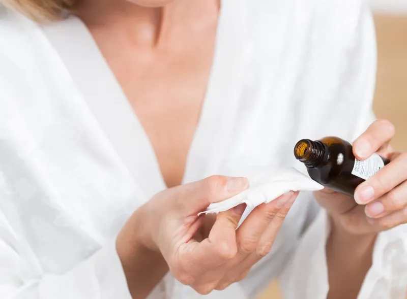 femme versant de l'huile essentielle dans un mouchoir