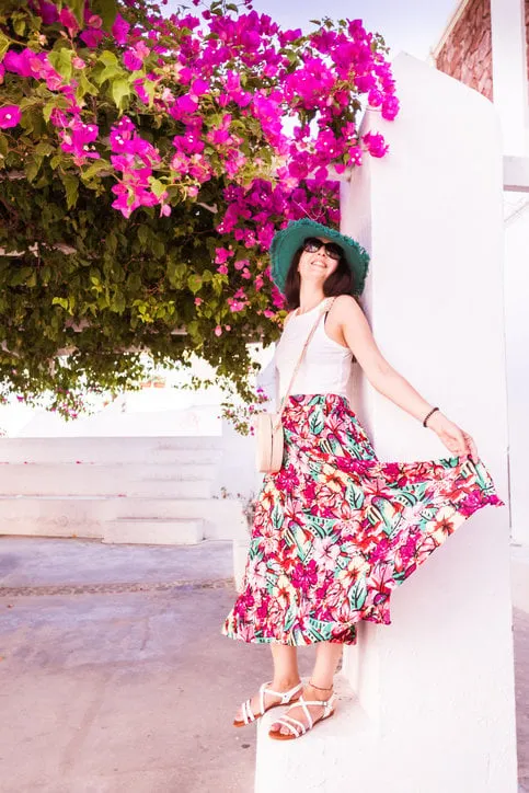 girl posing in oia with a green hat and a midi skirt