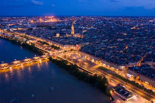 aerial view of bordeaux cityscape on banks of garonne river and pont de pierre at night