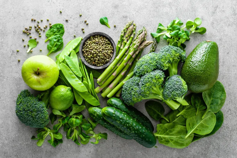 healthy vegetarian food concept background, fresh green food selection for detox diet, raw broccoli, apple, cucumber, spinach, peas, asparagus, avocado, lime, corn salad and mung bean, view from above, flat lay