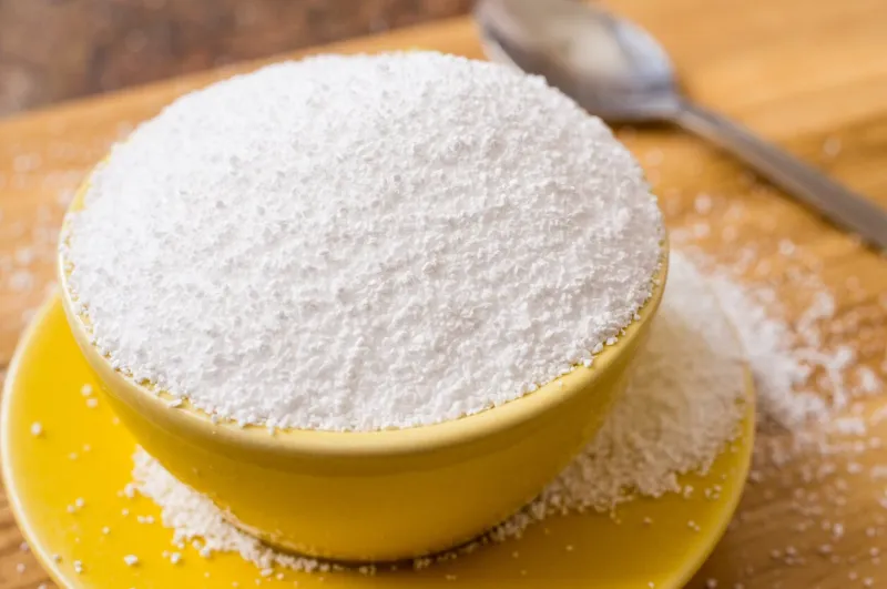 cup of sorbitol, a natural sweetener on the table next to a spoon closeup