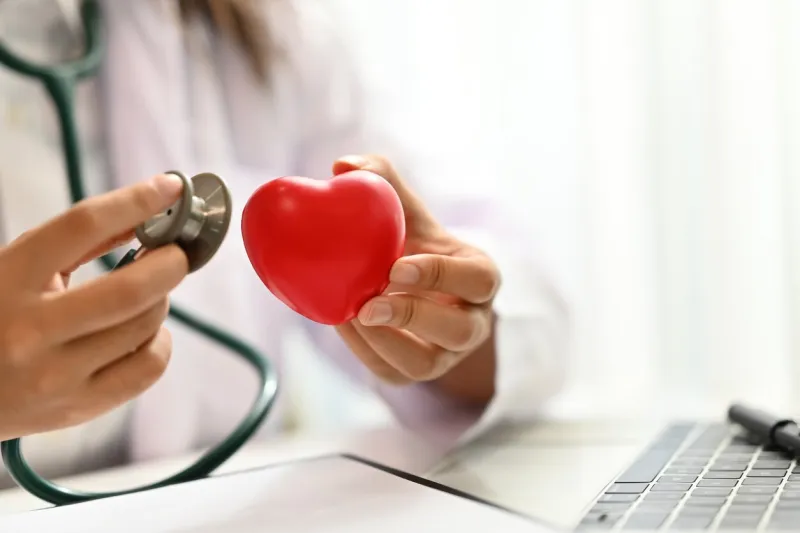 close up doctor holding stethoscope and red heart cardiac medical checkup, health care and medical concept