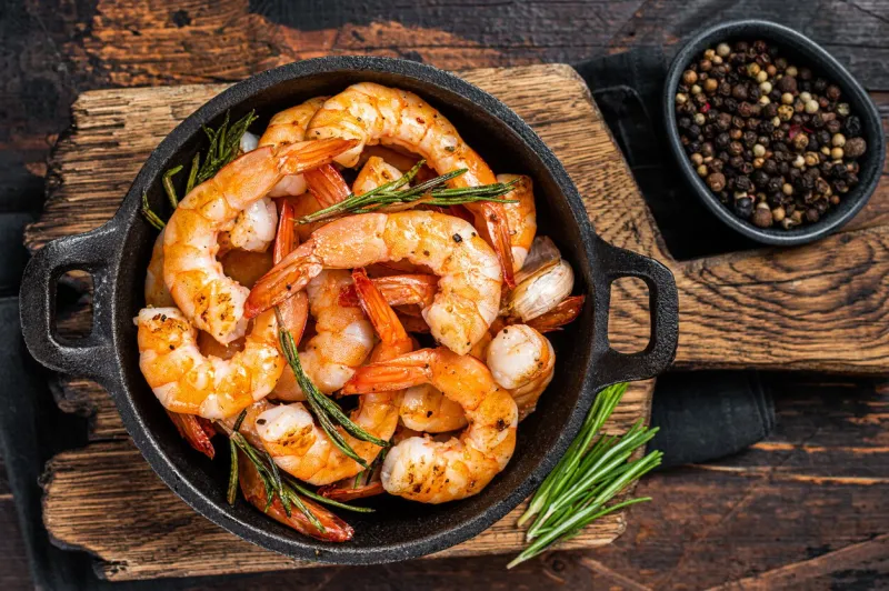 roast prawns shrimps in a pan with herbs and garlic dark wooden background top view