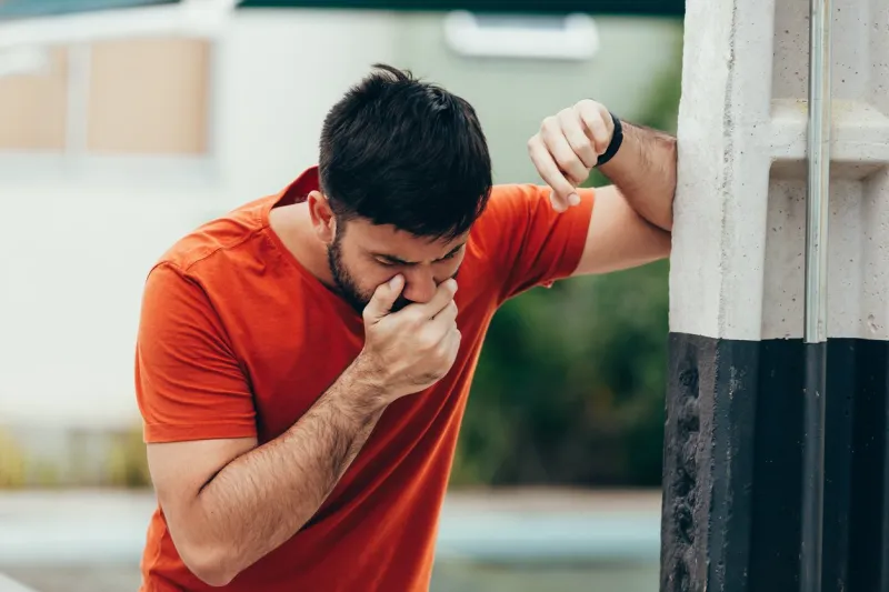 portrait of young man drunk or sick vomiting outdoors