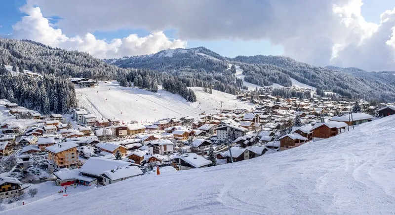 idyllic ski resort les gets in the french alps in wintry landscape and people skiing down the slopes shot from the mont chery