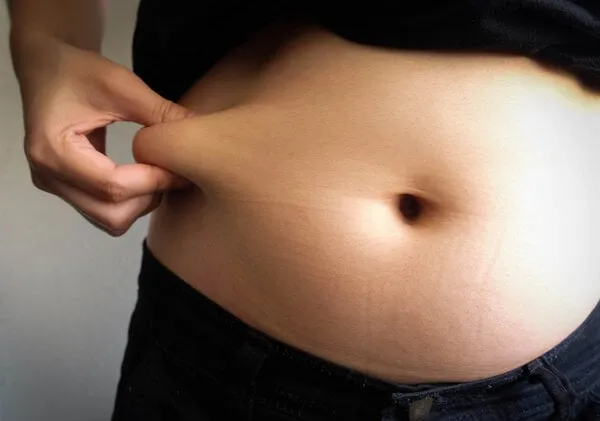 woman hand catching fat body belly paunch , diabetic risk factor
