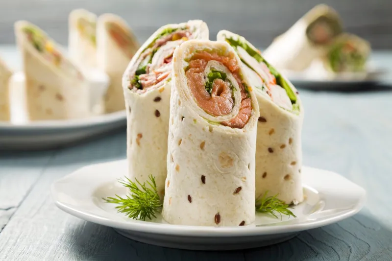 mix of wraps with ham, chicken, salmon and crab served on a plate
