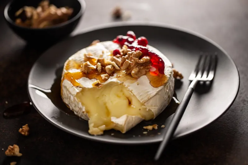 closeup of tasty baked camembert with nuts and cranberries