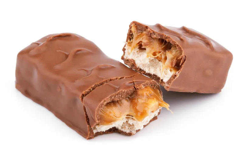 closeup of broken chocolate bar (nougat topped with caramel, enrobed in milk chocolate) isolated on white background