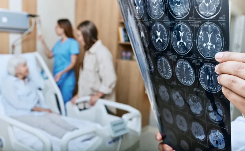 mri of head of elderly woman in hands of doctor standing in medical ward near senior patient with relative and nurse recovery after a stroke