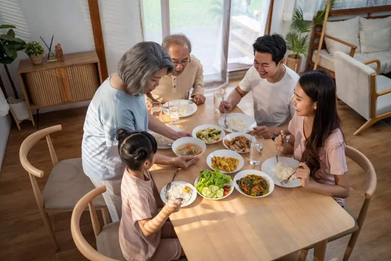 big asian happy family spend time having lunch on dinner table together little kid daughter enjoy eating food with father, mother and grandparents multi-generation relationship and activity in house