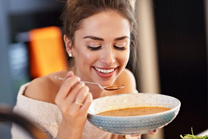 picture of adult woman tasting pumpkin soup in the kitchen