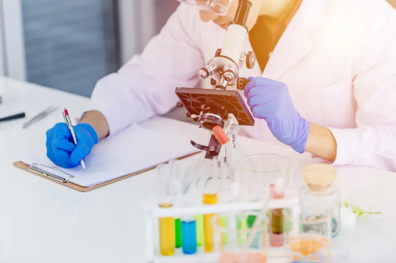 closeup scientist doctor working in lab and taking note or writing research paper work in medical school lab