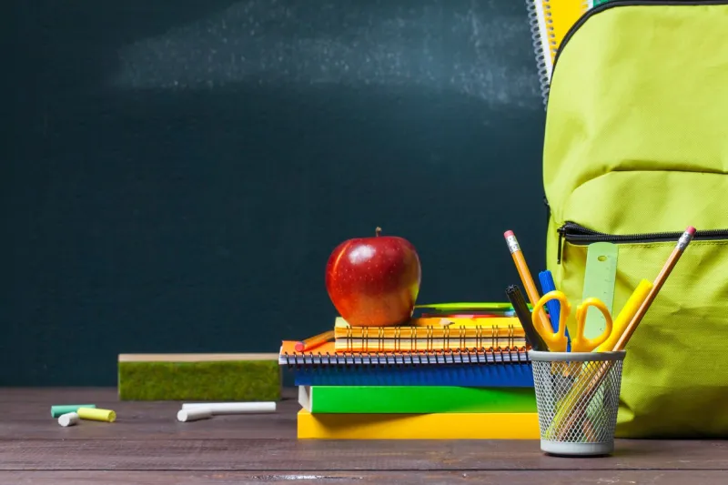 stack of books, stationery and education supplies on wooden desk back to school concept