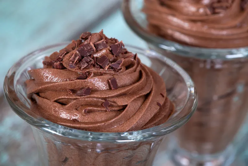 dark chocolate mousse dessert served in glass bowl, close up vintage green table background