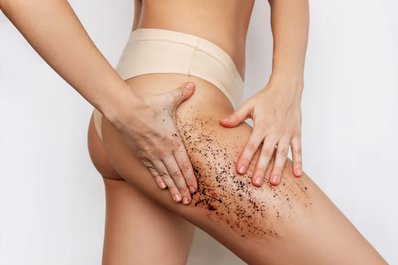 cropped shot of young slender tanned woman massaging her thigh w