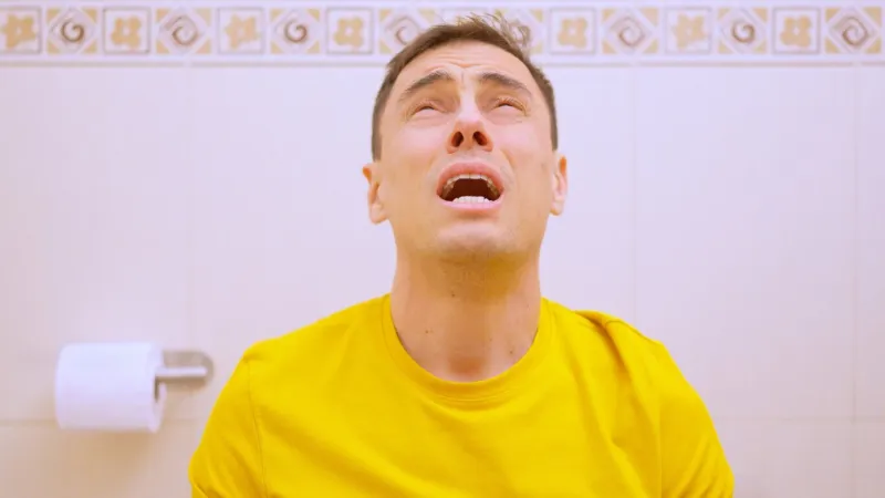 man experiencing severe stomach pain while using the toilet, highlighting digestive problems and discomfort